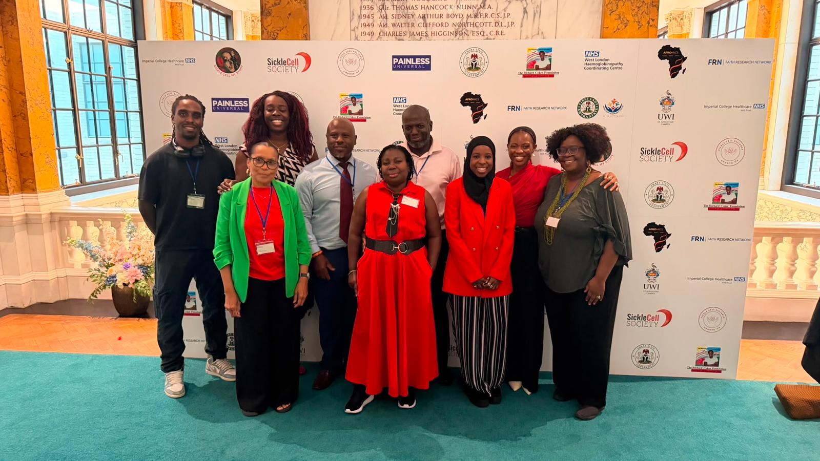Attendees of the World Sickle Cell Day event at Camden Hall in front of a branded backdrop